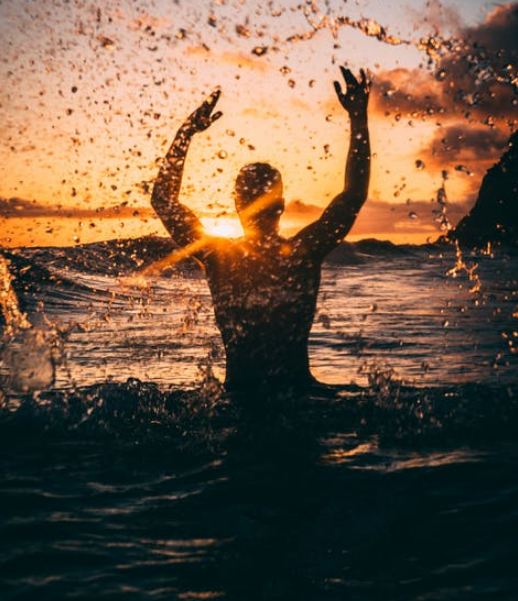Man swimming at a beach during sunset