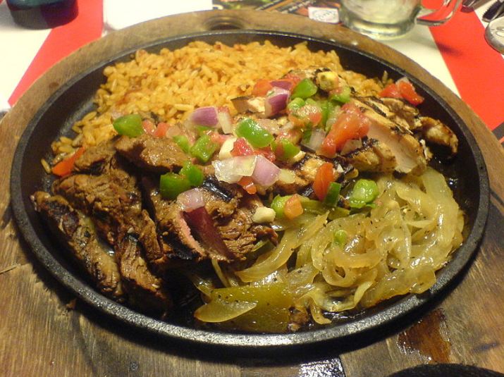 mixed platter of beef and chicken fajitas with onions and rice