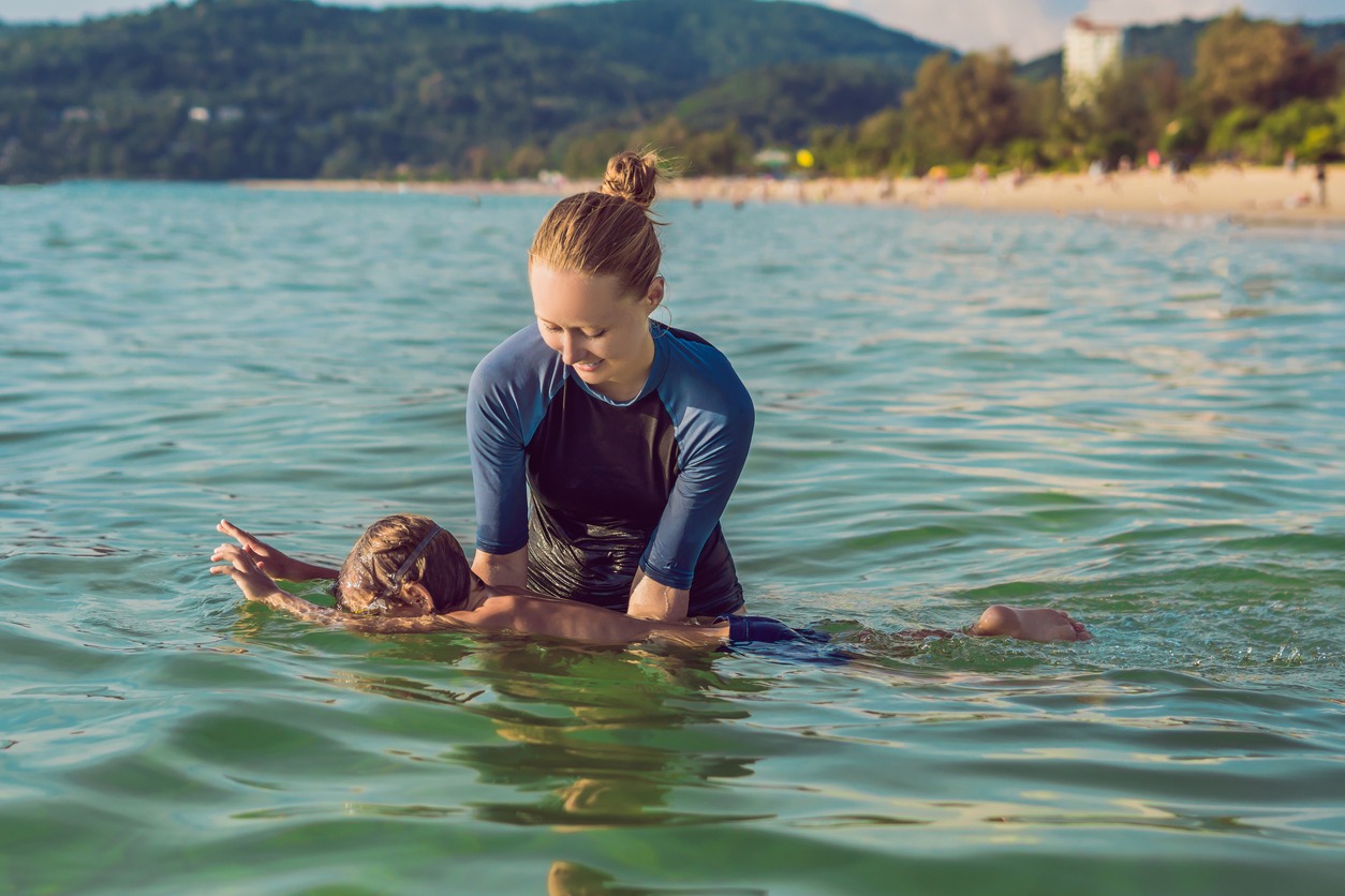 Woman swimming instructor for children is teaching a happy boy