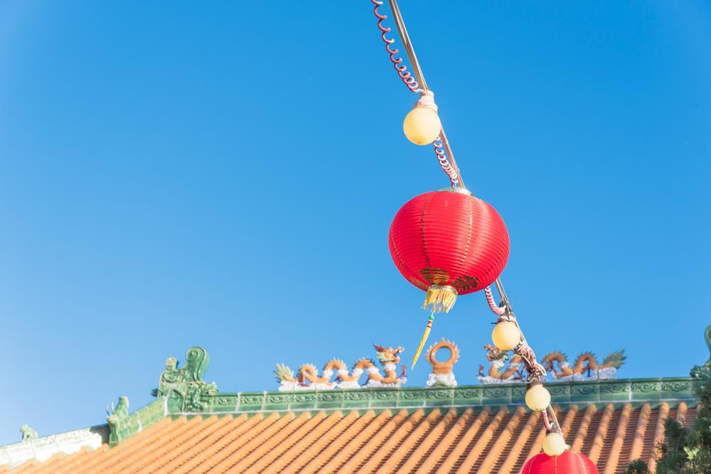 Bright red lanterns hanging near ancient clay tiles roof at Asian temple in Houston, Texas