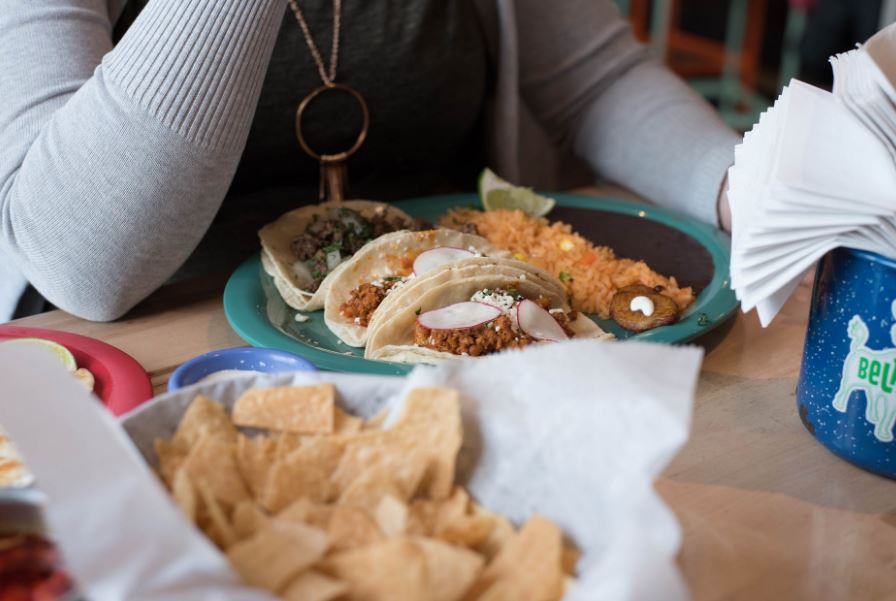 a person sitting in front of tacos on a plate