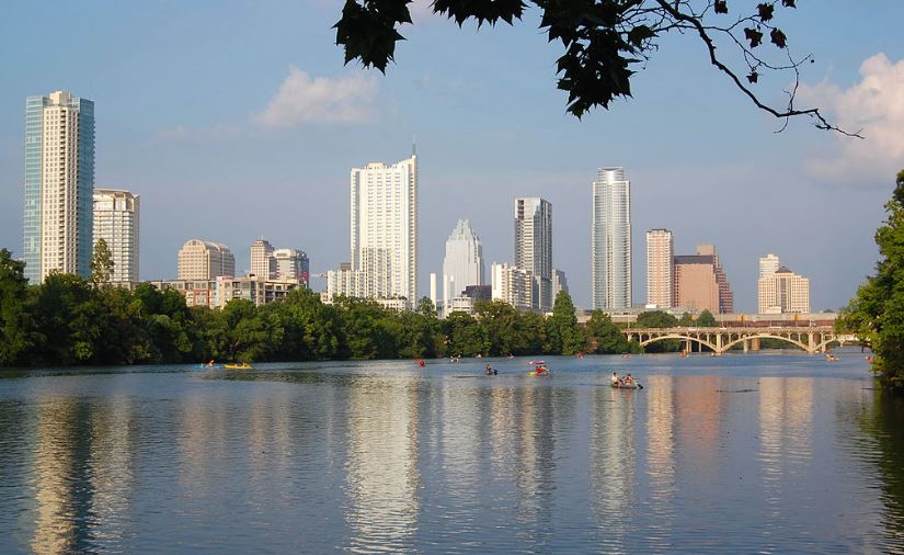 view from Lady Bird Lake toward Downtown Austin, people boating on the lake