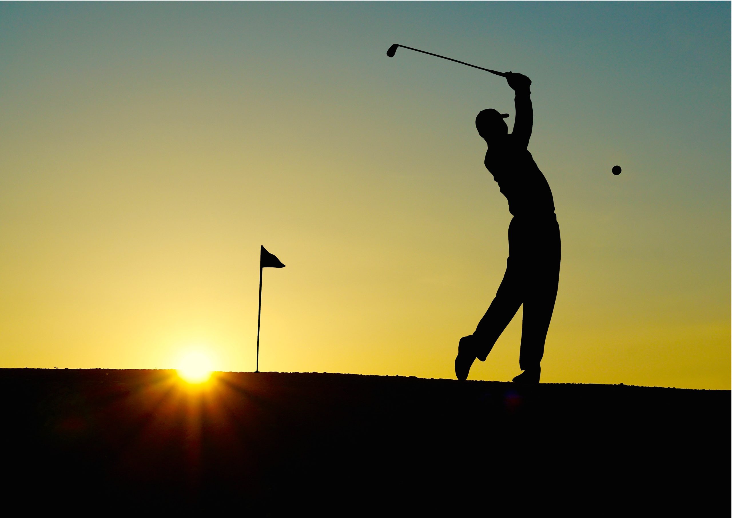 the silhouette of a man playing golf during sunset