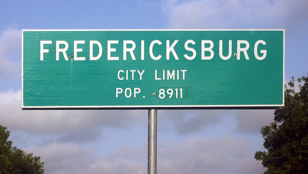 a green, huge signage with text FREDERICKSBURG City Limit Pop. 8911