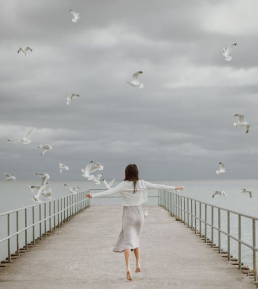 An image of a woman with flying Seagulls