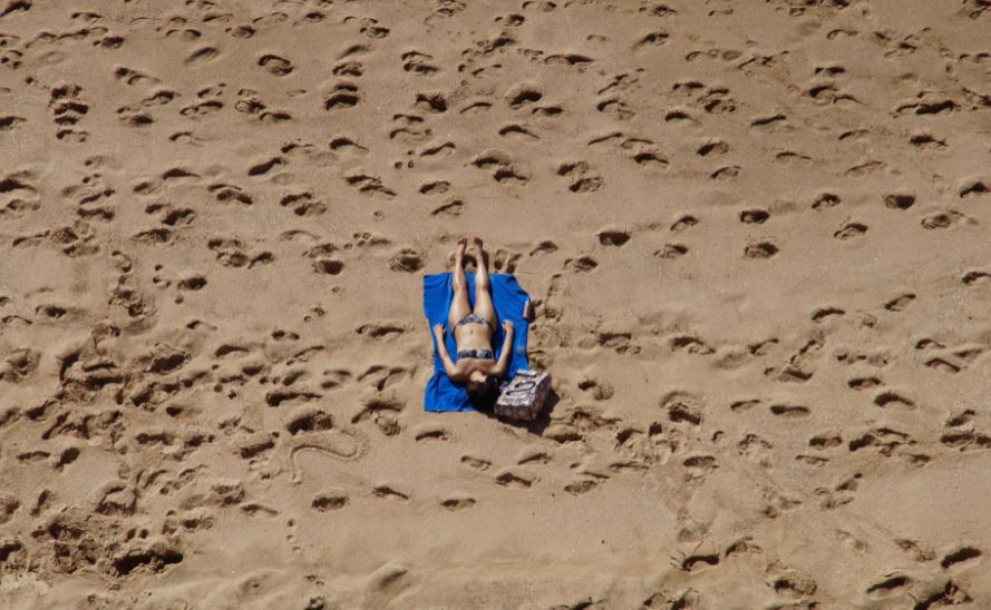 an aerial photo of a woman sunbathing at the beach