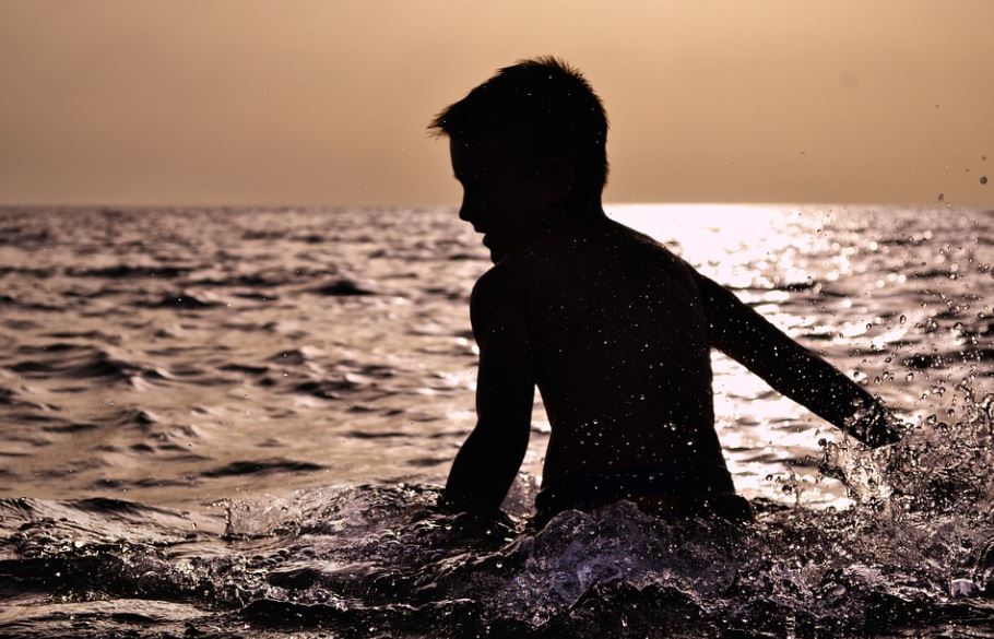silhouette of a boy, boy standing in the sea, ocean water