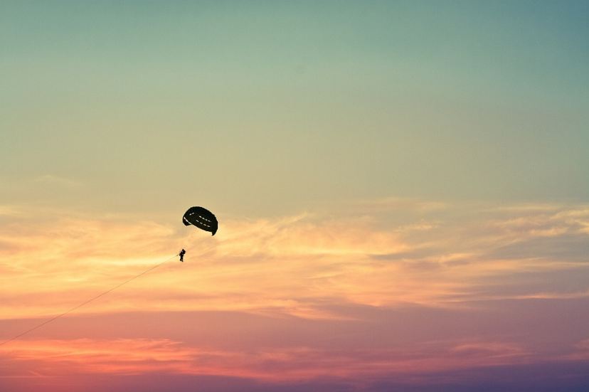 sky, person parasailing, the silhouette of a person, the silhouette of a parachute