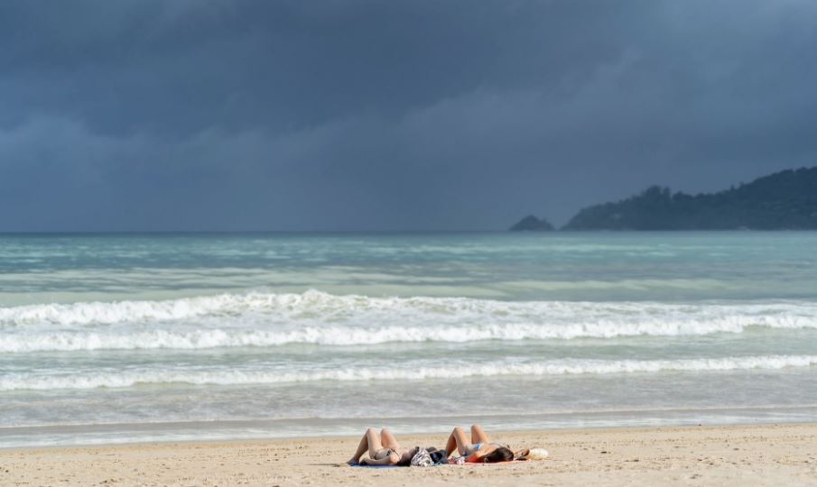 two people sunbathing at the beach