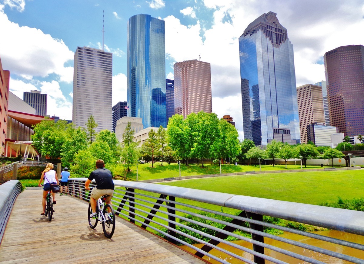 couple riding bikes across bridge in downtown Houston Park