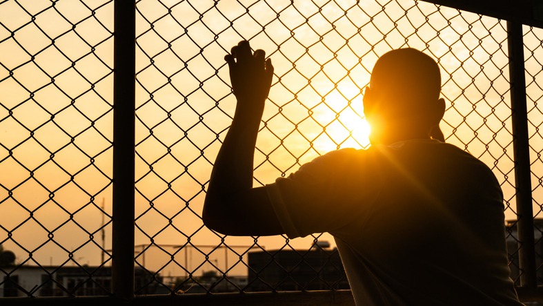 Silhouette of a man behind the fence