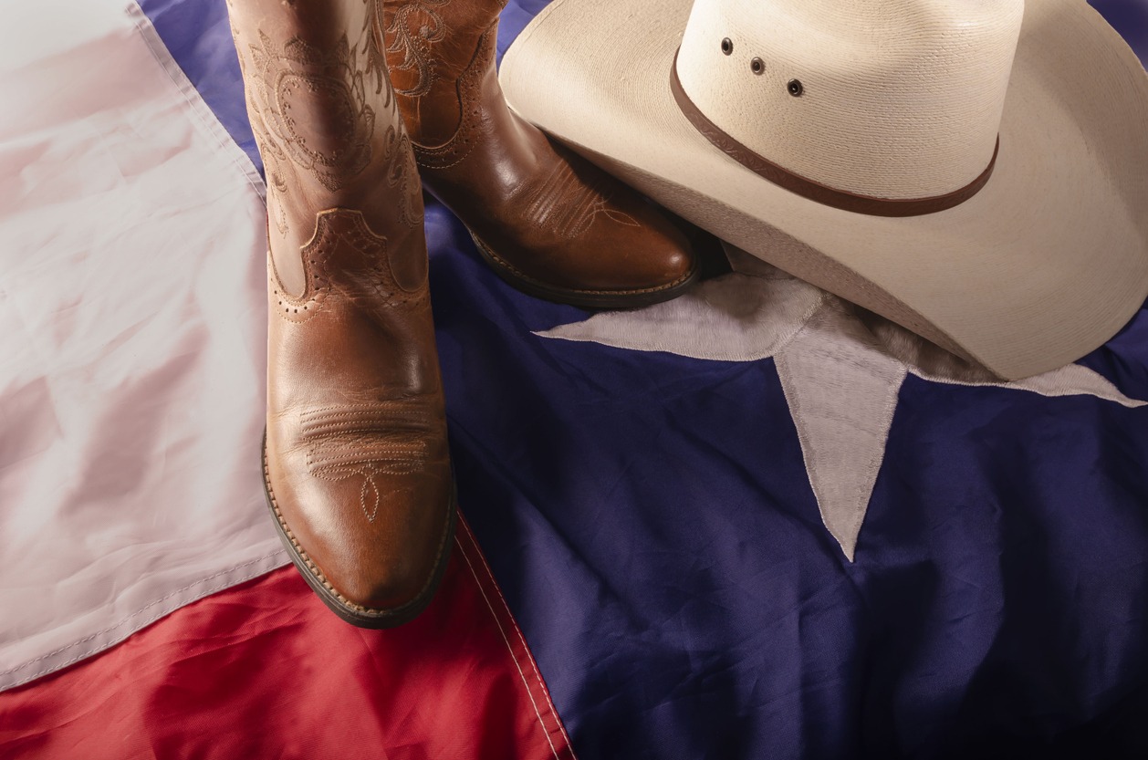 cowboy boots and hat on a Texas flag