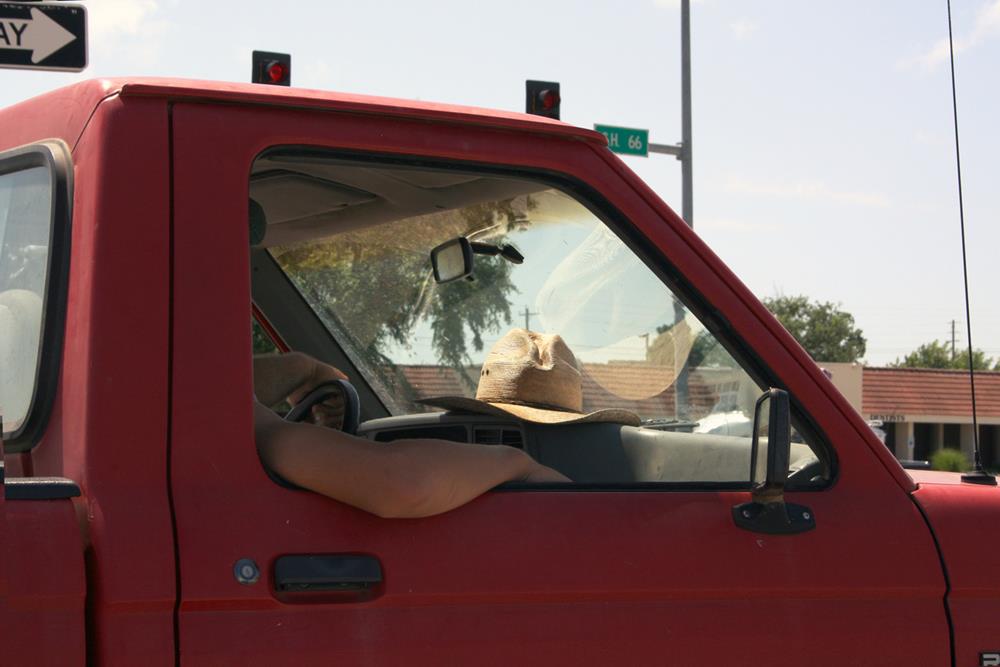 A pickup truck with a cowboy hat on the dashboard